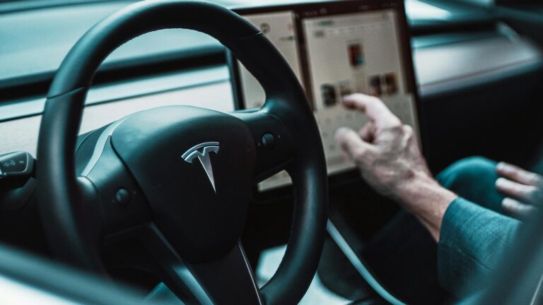 Driver using Tesla touchscreen in car
