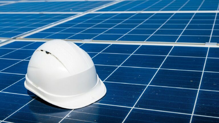 A white hard hat on blue solar panels