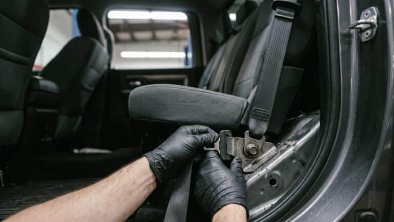 Technician inspecting a Ram 1500 recall seat belt anchor inside a truck cabin, chrysler recalls