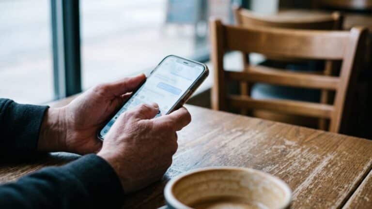 Hands holding a smartphone at a café table, illustrating dating app burnout, nearly 4