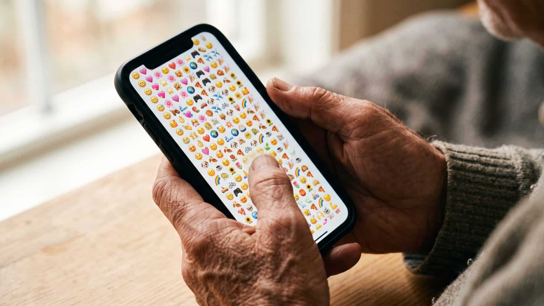 Hands holding a smartphone showing emoji-filled text messages, emoji brain, all text