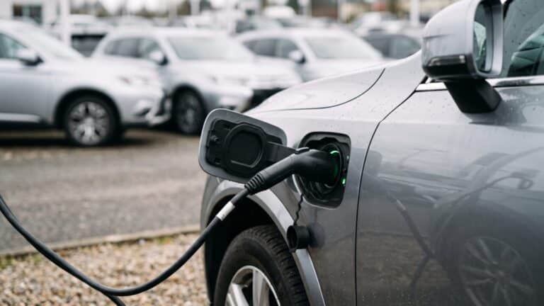plug-in hybrid charging cable connected to an SUV at a dealership lot