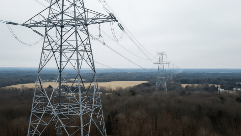 High-voltage transmission towers crossing a New England landscape under overcast sky, small percentage