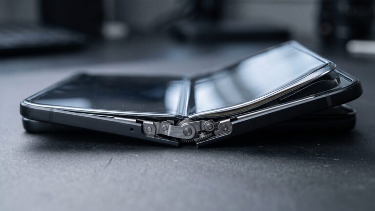 Close-up of a foldable iPhone hinge mechanism partially open on a studio surface