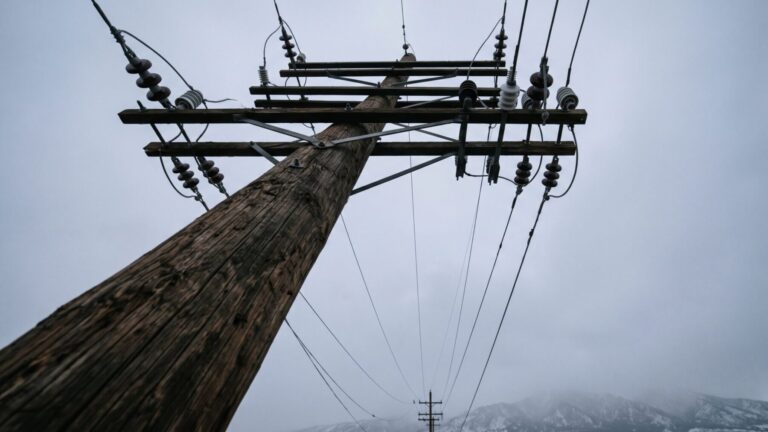 Utility pole and power lines under grey sky illustrating an electric rate increase, colorado puc