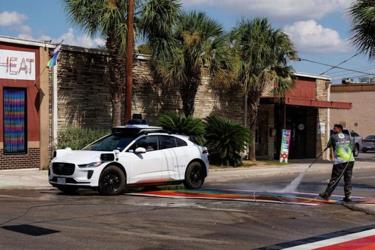 Autonomous robotaxi stopped at the edge of a flooded highway lane in wet conditions, waymo recall