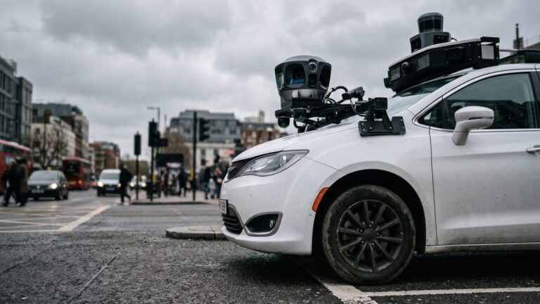 Waymo robotaxi with rooftop sensor dome at a city intersection