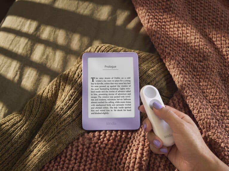 Hand pressing the Kindle Click remote beside an e-reader
