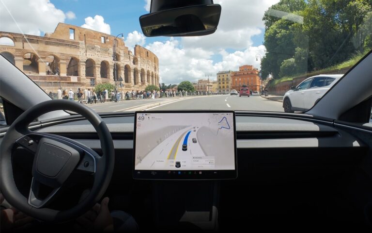 Driver hands near wheel as Assisted Driving display glows on dashboard