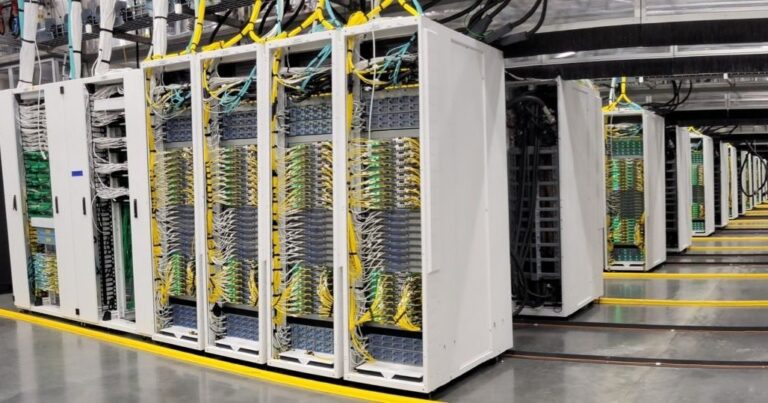 Server racks inside a linked AI superfactory data center, crews linked
