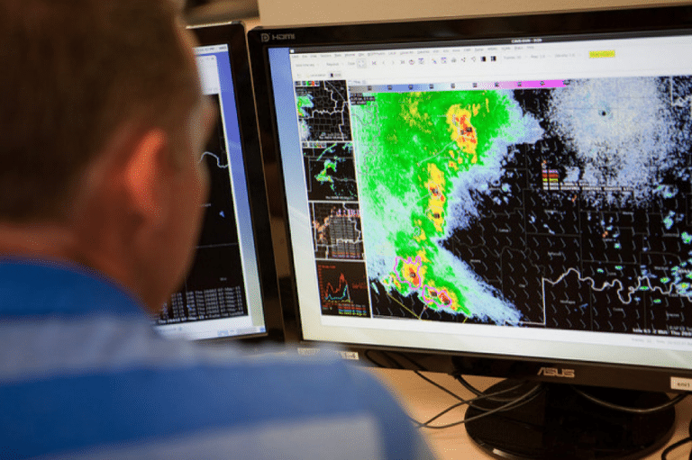 Developer reviewing open source disaster forecasting code on screens, google opens