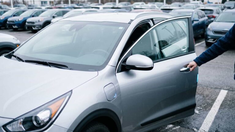 A row of hybrid cars on a dealership lot under overcast light, hybrids claimed