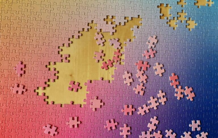 Hands sorting interlocking jigsaw puzzle pieces on a table