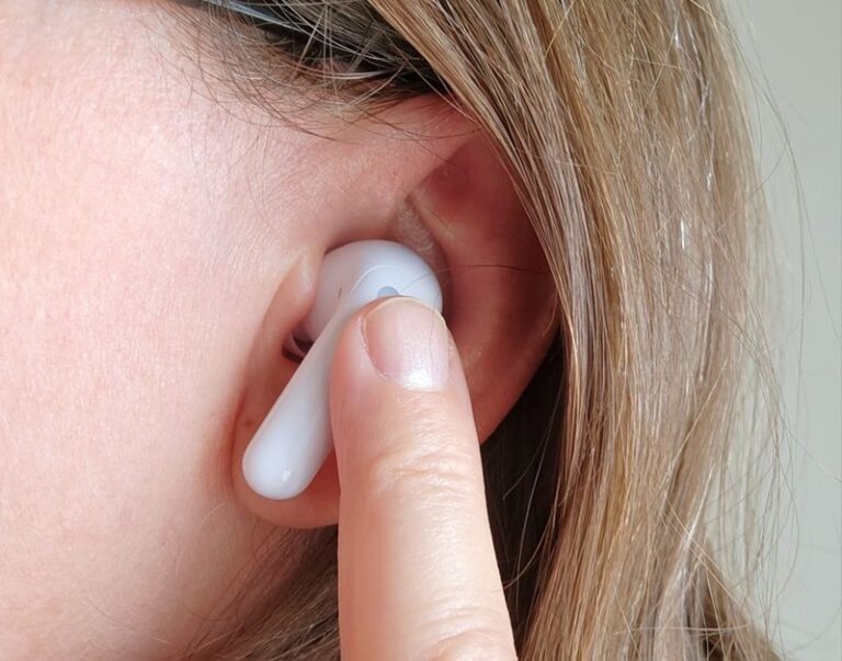 Hand holding translation earbuds with charging case on a table, earbuds promises