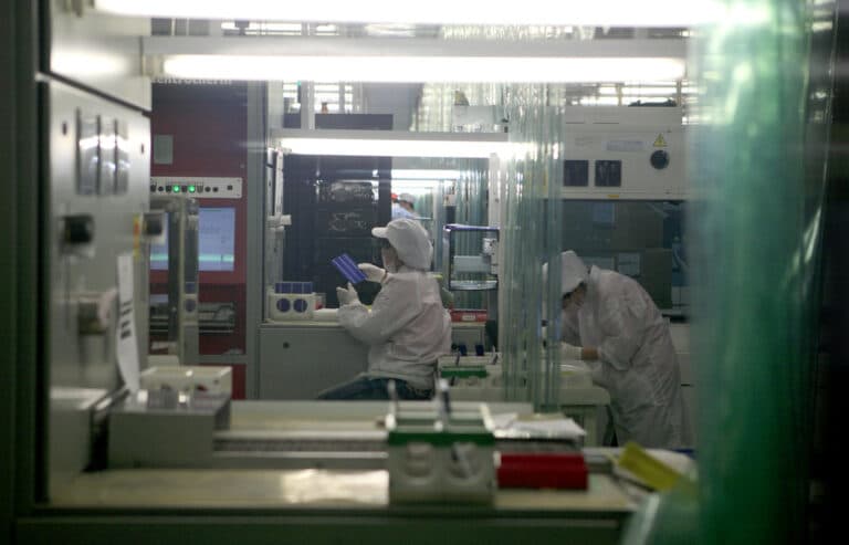 Hands holding a rectangular silicon wafer used in solar panels