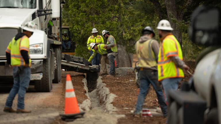 Crew burying a power line cable in a roadside trench, single buried