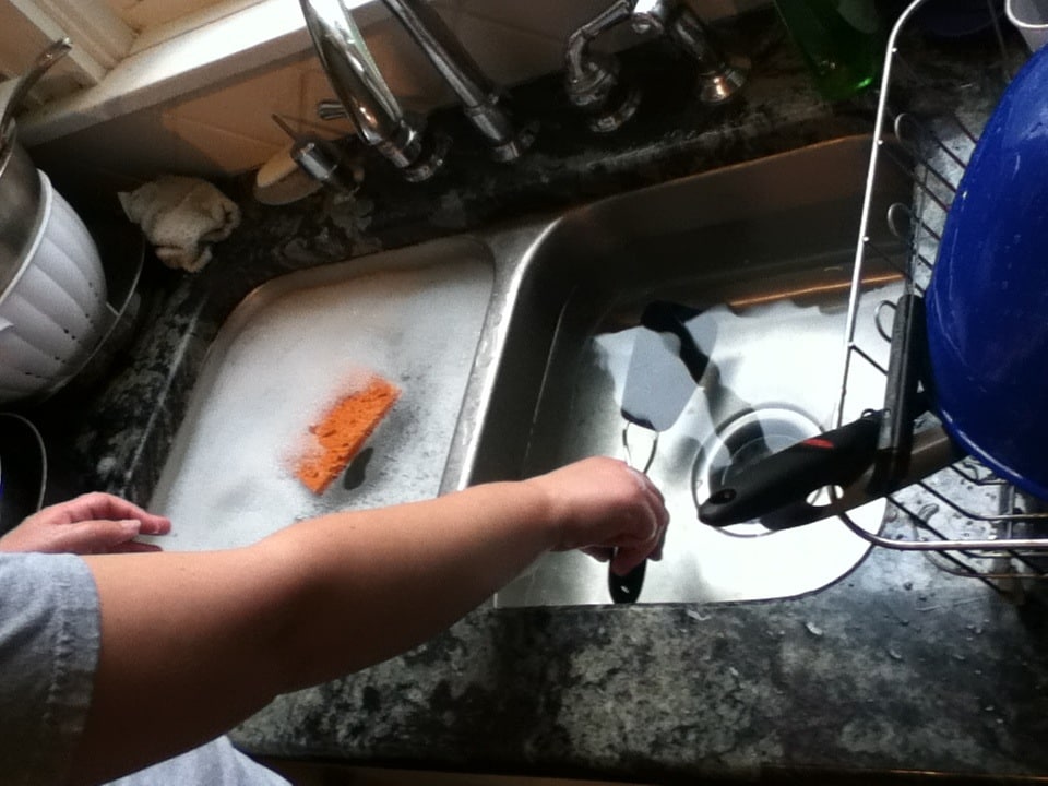 Sink full of 18 plates gets washed slowly by college students in a kitchen lab test, and the mindful scrubbers report 27 percent less nervousness afterward