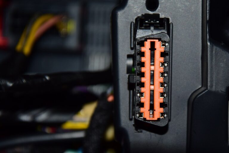 Hand installing a fleet GPS tracking device under a van dashboard, small plug